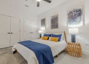 Thumbnail 8 of 33 - A bedroom with a bed, a ceiling fan, and a wicker stool.