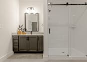 Thumbnail 11 of 33 - A bathroom with a mirror, vanity, and shower.