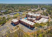 Thumbnail 16 of 33 - A large red building with a pool in the middle surrounded by a parking lot.