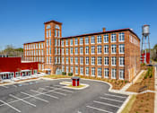 Thumbnail 33 of 33 - A large red brick building with a water tower in the background.