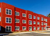 Thumbnail 30 of 33 - A red building with a parking lot in front.