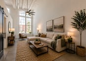 Thumbnail 9 of 33 - A living room with a couch, a chair, a table, and a potted plant.