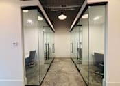 Thumbnail 26 of 33 - A hallway with glass walls and a grey chair.