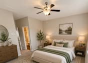 Thumbnail 30 of 71 - A bedroom with a large bed, a ceiling fan, and a painting on the wall.