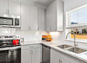 Thumbnail 11 of 48 - A kitchen with white cabinets and a black stove top oven.