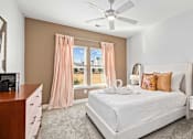 Thumbnail 17 of 48 - A bedroom with a large bed, a dresser, and a ceiling fan.