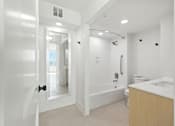 Thumbnail 30 of 40 - A white bathroom with a tub, toilet, and sink.