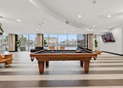 Thumbnail 19 of 40 - A billiard table is in the middle of a room with a view of the city.