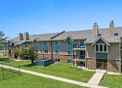 Thumbnail 4 of 29 - the view of an apartment building with a lawn and a fence