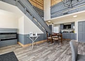 Thumbnail 3 of 18 - a living room with a table and chairs and a kitchen with a staircase