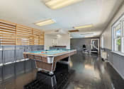 Thumbnail 14 of 18 - a game room with a pool table and a gym with a wheelchair