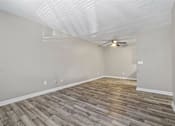 Thumbnail 9 of 18 - the spacious living room with wood flooring and a ceiling fan
