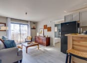 Thumbnail 9 of 27 - a living room with a couch and a table and a refrigerator at The Lodge Apartments, Tulsa Oklahoma