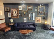 Thumbnail 1 of 27 - a living room with a black couch and a wall filled with paintings and mirrors at The Lodge Apartments, Tulsa, OK 74129