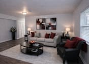 Thumbnail 1 of 9 - A living room with a grey couch, a black chair, and a coffee table.