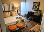 Thumbnail 5 of 22 - A bedroom with a bed, desk, and chair.