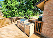 Thumbnail 10 of 22 - A wooden deck with a grill and a cooler on it.