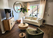 Thumbnail 4 of 22 - A living room with a white couch and a wooden coffee table.