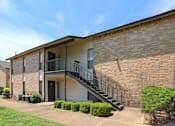 Thumbnail 11 of 11 - A brick building with a balcony and stairs leading to the entrance.
