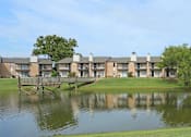 Thumbnail 1 of 11 - A row of houses with a bridge over a pond in front.
