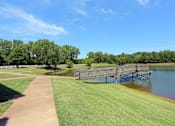 Thumbnail 8 of 11 - A wooden bridge over a body of water with a grassy area on the left.