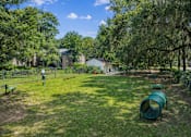 Thumbnail 16 of 17 - A playground with a slide and a green barrel in the foreground.