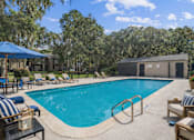 Thumbnail 17 of 17 - A pool surrounded by chairs and umbrellas with a building in the background.