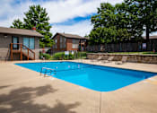 Thumbnail 31 of 35 - A blue swimming pool surrounded by a fence and trees.