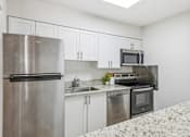 Thumbnail 4 of 17 - A kitchen with a stainless steel refrigerator, microwave, oven, and sink.