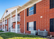 Thumbnail 1 of 14 - A row of red brick apartment buildings with white balconies.