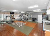 Thumbnail 10 of 14 - A spacious room with a variety of exercise equipment and a kitchen area.
