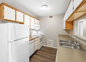 Thumbnail 11 of 14 - A kitchen with white appliances and wooden cabinets.