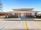 Thumbnail 9 of 14 - A building with a parking lot in front of it.