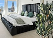 Thumbnail 4 of 40 - A bedroom with a large bed and a view of a city skyline.