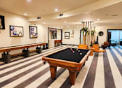 Thumbnail 27 of 40 - A pool table is in the middle of a room with striped flooring.