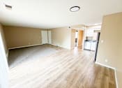 Thumbnail 33 of 35 - A spacious room with wooden flooring and a refrigerator in the corner.