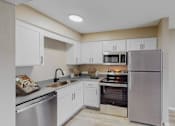 Thumbnail 2 of 35 - A kitchen with white cabinets and stainless steel appliances.