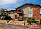 Thumbnail 19 of 35 - A brick building with a balcony and a stone wall.