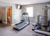 Thumbnail 23 of 35 - A home gym with a treadmill, weights, and exercise equipment.