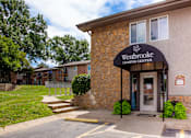 Thumbnail 24 of 35 - The front of the Westbrooke Leasing Center is shown with a stone facade and a green lawn.