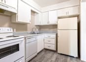 Thumbnail 13 of 35 - A white kitchen with a stove, sink, and refrigerator.