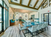 Thumbnail 29 of 49 - a dining room with blue tables and chairs and a kitchen with glass doors at Imperial Crossing Luxury Apartment Homes, Bonita Springs, FL, 34134