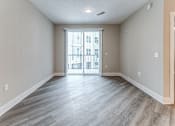 Thumbnail 22 of 31 - A spacious room with light wood flooring and a view of a balcony through a glass door.at Tiffany Flats, Ohio, 43231