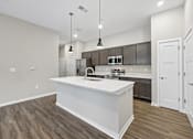 Thumbnail 24 of 57 - A modern kitchen with a white island and wooden floors.