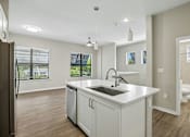 Thumbnail 7 of 71 - A kitchen with a white countertop and a black refrigerator.
