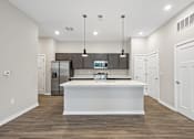 Thumbnail 1 of 57 - A modern kitchen with a white island and wooden floors.