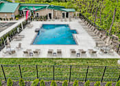 Thumbnail 45 of 57 - A large outdoor swimming pool surrounded by lounge chairs and a fence.
