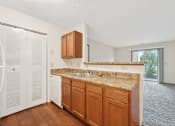 Thumbnail 7 of 41 - A kitchen with brown cabinets and a granite countertop.