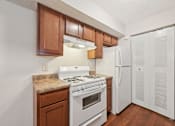 Thumbnail 10 of 41 - A kitchen with white appliances and wooden cabinets.