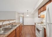 Thumbnail 11 of 41 - A kitchen with a white refrigerator, wooden cabinets, and a stainless steel sink.
